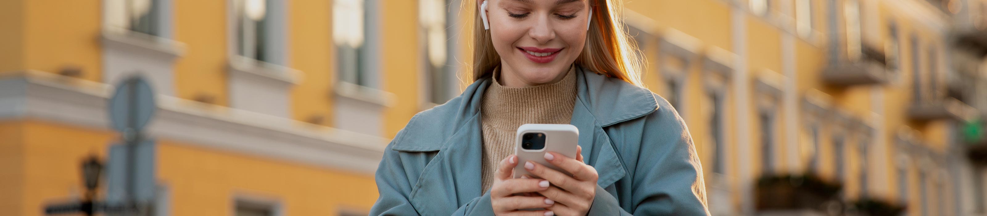 Junge Frau hält lächelnd Smartphone in der Hand