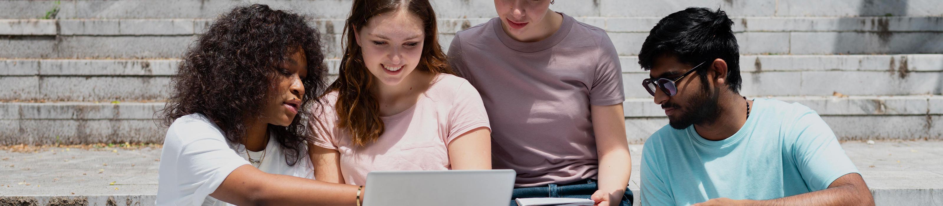 Vier teeanger sitzen gemeinsam vor einem Laptop