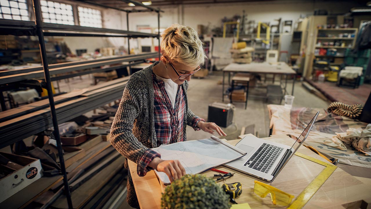 Frau in einer Werkstatt mit Laptop 